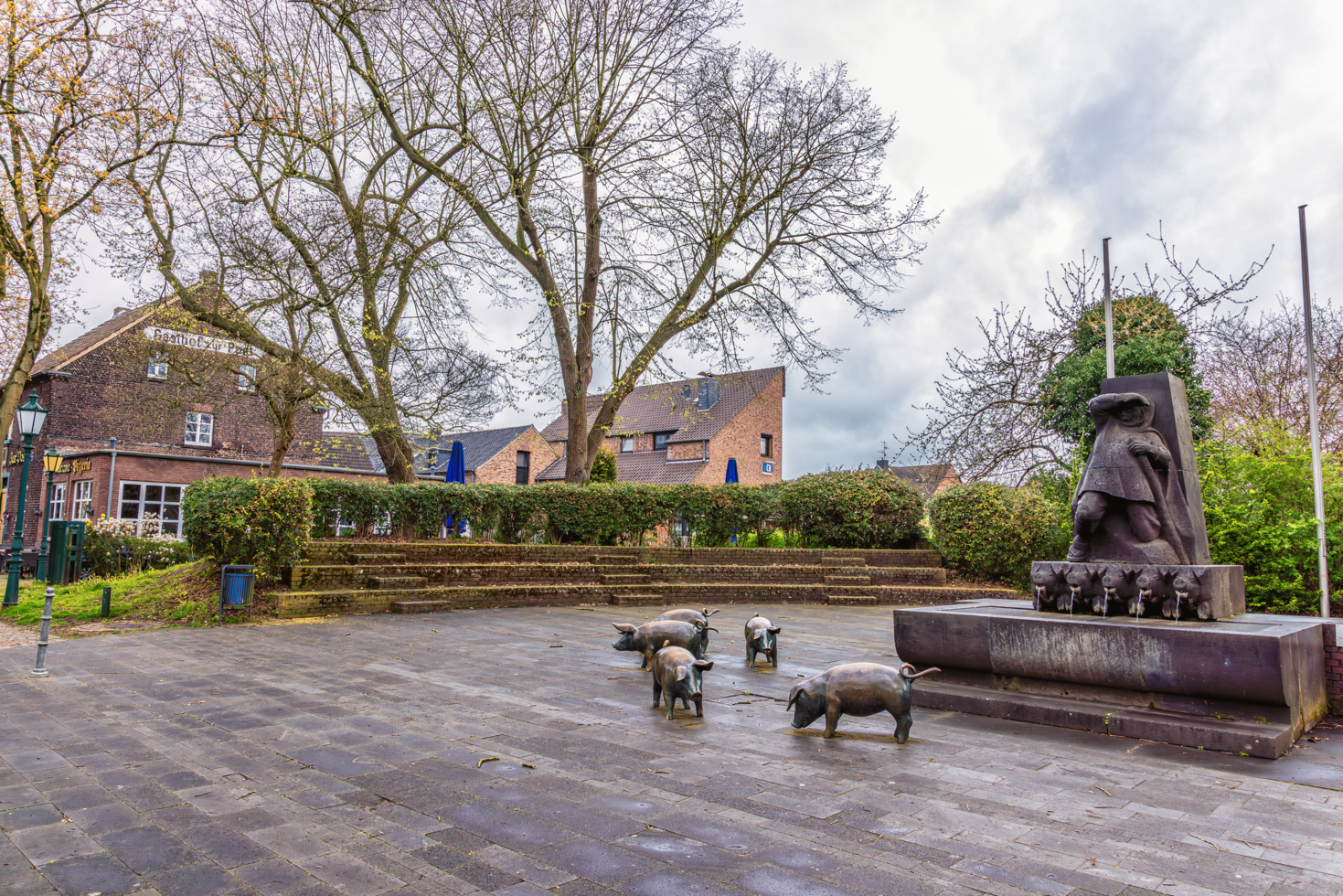2026-04-FCa-030-Schweinebrunnen-Zons Der Schweinebrunnen in Zons aus dem Jahr 1959 von Bildhauer Bernhard Lohf nimmt die historische Begebenheit der sogenannten "Zonser Schweinefehde" aus dem Jahr 1575/1577 auf, in der Soldaten des damaligen Kölner Erzbischof Salentin von Isenburg die Zonser Schweineherde, bestehend aus 50 Schweinen, stahlen