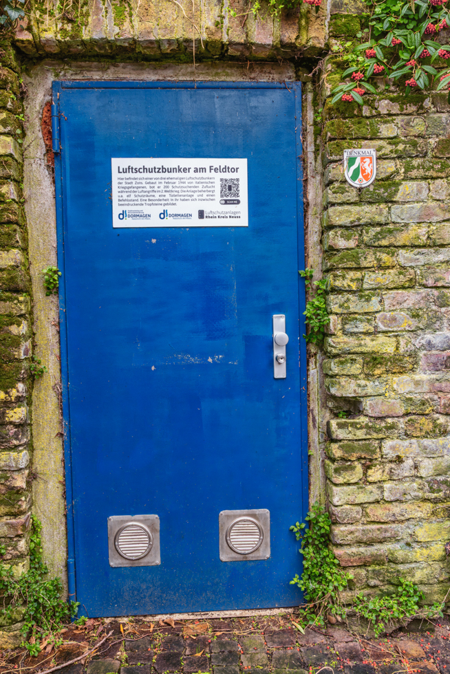 2026-04-FCa-033-Luftschutzbunker-Zons Eingang zu einem der drei ehemaligen Luftschutzbunker in Zons. Dieser ist der Bunker am Feldtor und kann im Rahmen von Führungen auch besichtigt werden