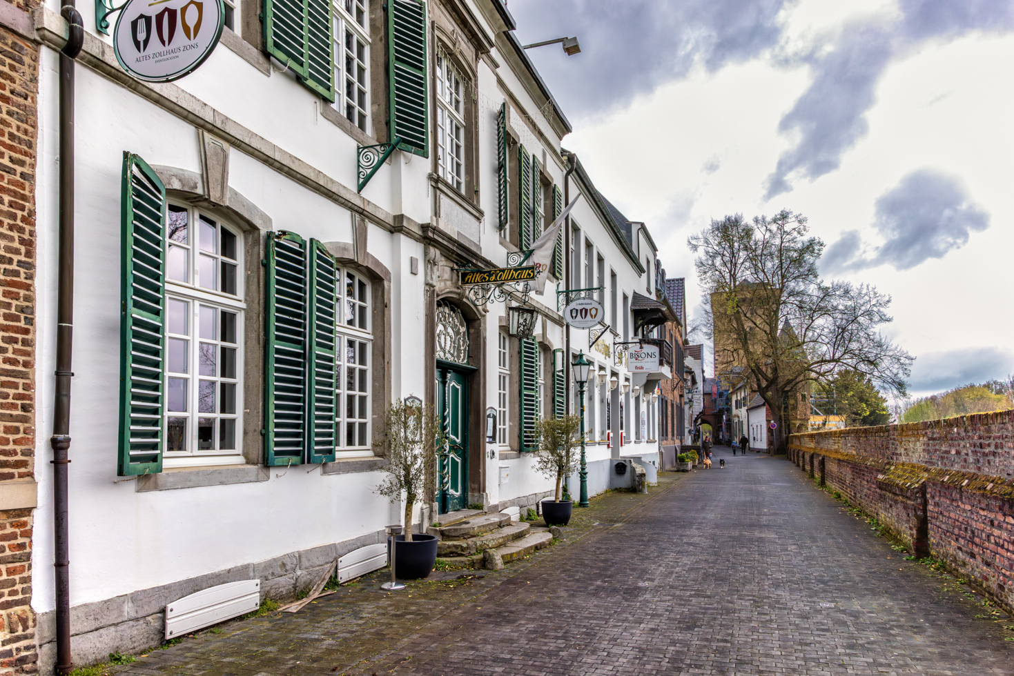 2026-04-FCa-045-Altes-Zollhaus-Zons Im Zonser Zollhaus wurde einst der Zoll erhoben. Das Zollrecht bestand im Mittelalter darin, von vorbeikommenden Reisenden und Händlern Zoll auf die per Schiff beförderten Waren zu erheben. Die Räumlichkeiten des Zollhauses dienten ab 1855 für über 100 Jahre als Klosteranlage unterschiedlicher Ordensgemeinschaften.